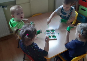 Filip, Zosia, Szymek i Zosia malują jeden z elementów pracy plastycznej.