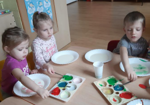 Blanka, Kornelia i Adam dodają farb do mleka tworząc kolorowe plamy.