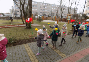 Kolorowy pochód wokół przedszkola z Marzanną i kwiatami.