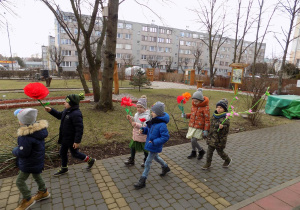 Kolorowy pochód wokół przedszkola z Marzanną i kwiatami.