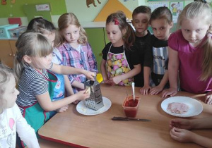 Dzieci przygotowują składniki na pizzę.