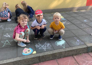 Dzieci tworzą obrazki na przedszkolnym tarasie.