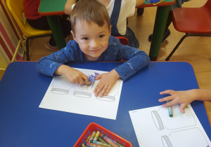 Chłopiec wykonuje ćwiczenie związane z owocami i warzywami.