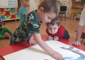 Mateusz odciska swoją dłoń na plakacie.