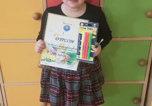 Julia z dyplomem i nagrodą za udział w konkursie.