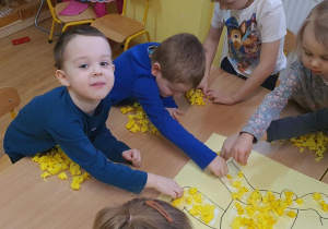 Filip i Jasio wyklejają nogi Kubusia Puchatka.