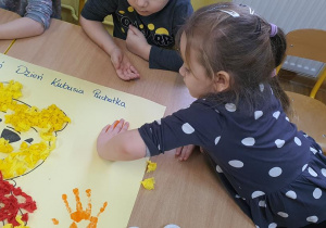 Basia podpisuje się pod wykonaną pracą stemplując swoją rączkę na plakacie.