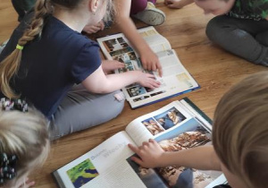 Dzieci oglądają w albumach ciekawe miejsca we Włoszech.