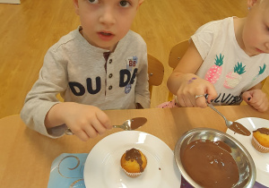 Filip pokrywa czekoladą swoją muffinkę.