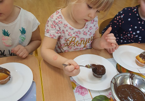 Gabrysia pokrywa czekoladą swoją muffinkę.
