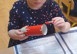 Basia maluje rolkę papierową na kolor czerwony.