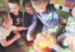 Dzieci zdejmują kolorowe gumeczki z dyni