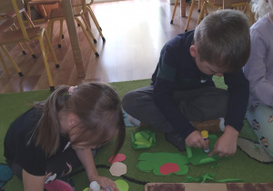 dzieci przyklejają warzywa na wcześniej przygotowane poletko z papieru