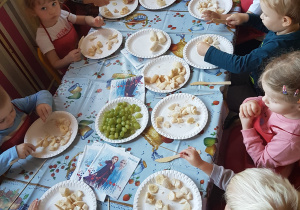 Dzieci przygotowują szaszłyki owocowe.