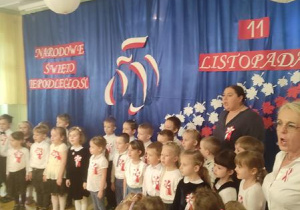 Dzieci z nauczycielami śpiewają hymn Polski.