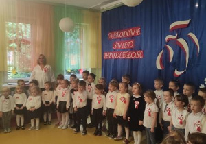Dzieci z nauczycielami śpiewają hymn Polski.