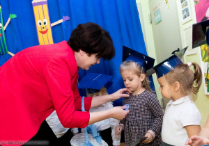 Pani Aneta Pietrzak wręcza dzieciom emblematy przedszkola- grupa Żuczki.