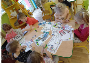 Dzieci wycinają zabawki z gazet i przyklejają na list do Mikołaja