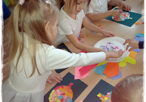 Dzieci wyklejają bombki kawałkami papieru