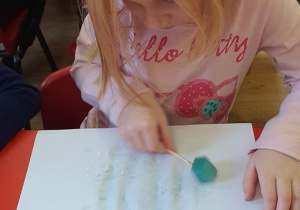 Martynka maluje lodowymi farbami.