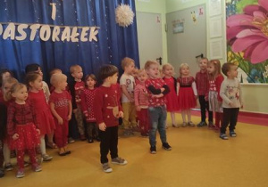Dzieci stoją przed dekoracją i śpiewają piosenkę.
