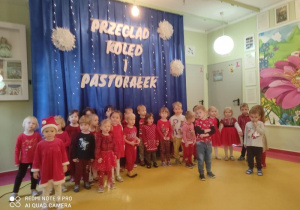 Dzieci stoją przed dekoracją i śpiewają piosenkę.