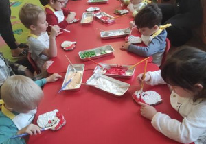 Dzieci dekorują Mikołaje.