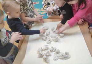 Dzieci naklejają na karton kulki z chusteczek.