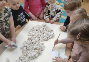 Dzieci naklejają na karton kulki z chusteczek.