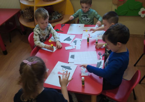 Dzieci układają bałwanka i przyklejają na kartkę