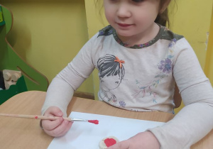 Marysia maluje farbami serduszko z masy solnej