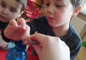 Maks wsypuje brokat do butelki sensorycznej