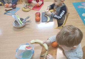 Dzieci obierają i kroją owoce.