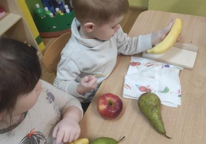 Dzieci obierają i kroją owoce.
