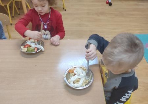 Dzieci zjadają sałatkę.