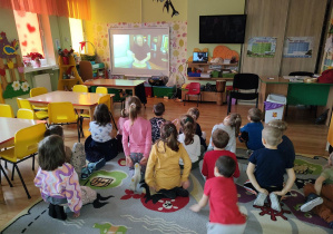 Dzieci oglądają film instruktażowy, pokazujący sposoby gry na bębnie