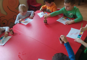 Dzieci malują farbami obrazki dinozaura