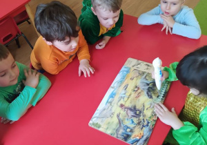 Dzieci oglądają książkę i słuchają odgłosów dinozaurów