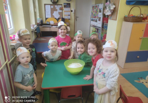 Dzieci stoją wokół stolika na którym stoi miska z przygotowana masą solną.