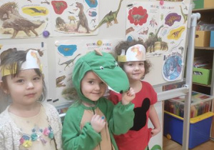 Dzieci pozują z dinusiem Adą w kolorowych opaskach na głowach.