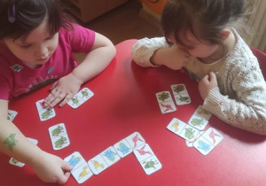 Hania z Marysią grają w domino z dinozaurami.