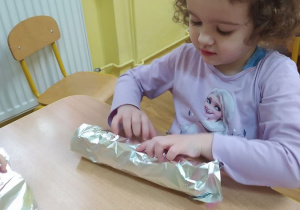 Lila zawija rolkę papierową w folię aluminiową