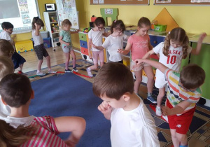 Dzieci poruszają się w rytm muzyki po szarfach.
