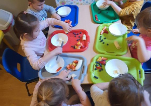 Dzieci samodzielnie kroją owoce do sałatki.