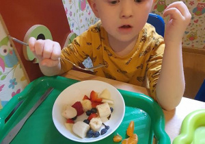 Jeremi zajada sałatkę owocową.
