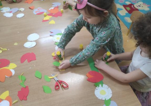 Dzieci wykonują kwiatową girlandę.