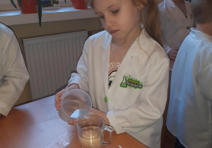 Kornelia umieszcza jajko w szklance ze słodką wodą.