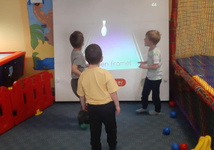 Adaś, Witek i Antek grają na tablicy interaktywnej.
