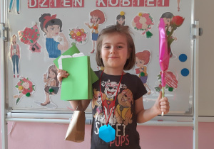 Zosia prezentuje swoje upominki- laurkę, medal, prezent oraz tulipana.