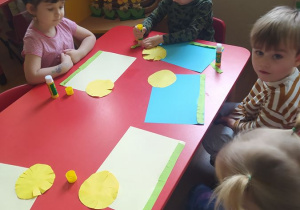 Dzieci przyklejają wycięte elementy na kartce